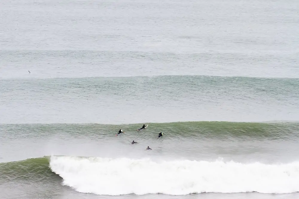5 surfers paddling out in the lineup at Porto Batel